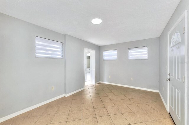 spare room with a textured ceiling and light tile patterned floors