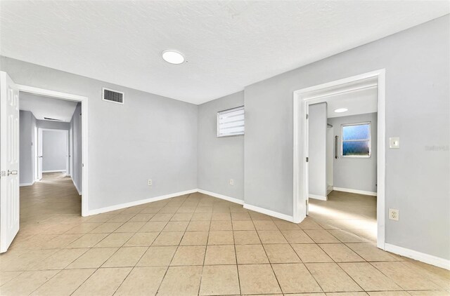 unfurnished room with a textured ceiling and light tile patterned floors