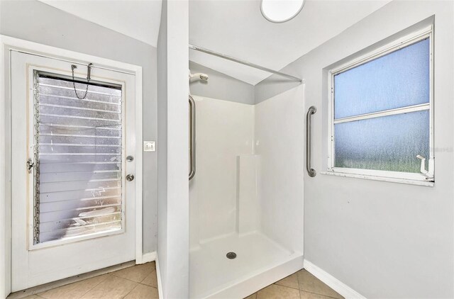 bathroom with tile patterned flooring, vaulted ceiling, and a shower