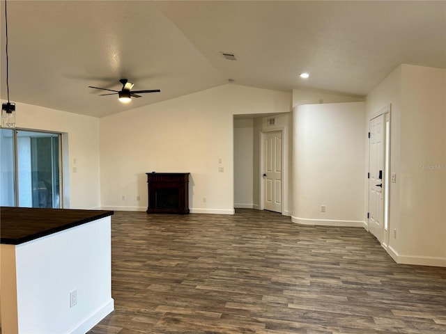 unfurnished living room featuring ceiling fan, vaulted ceiling, a fireplace, and dark wood-type flooring