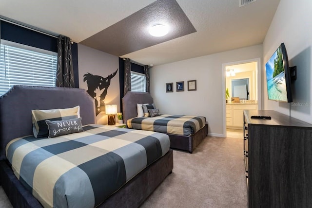 bedroom with light carpet, a textured ceiling, and ensuite bathroom