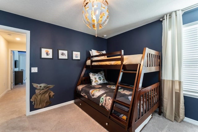 bedroom with multiple windows, light colored carpet, and a textured ceiling