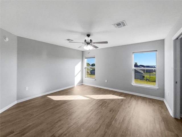 unfurnished room featuring a healthy amount of sunlight, dark hardwood / wood-style floors, and ceiling fan