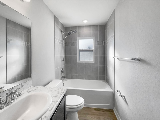 full bathroom with tiled shower / bath combo, vanity, toilet, and hardwood / wood-style flooring