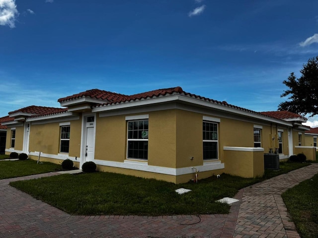 view of side of property with a lawn and cooling unit