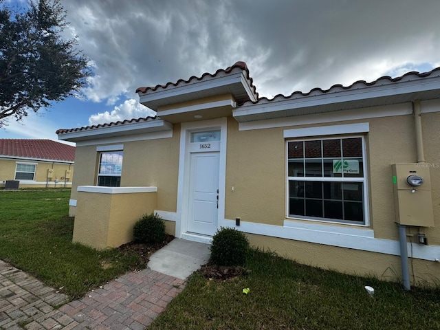 view of exterior entry featuring central AC unit and a lawn