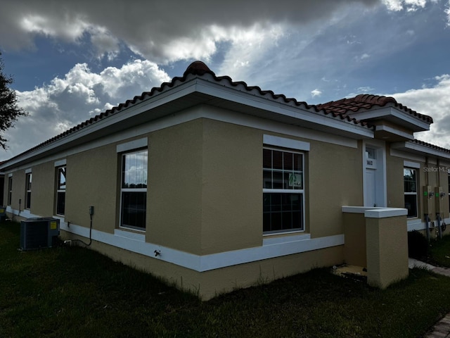 view of side of property featuring a yard and central AC unit