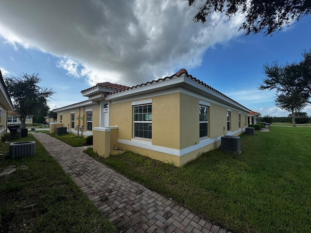 view of side of home featuring a lawn and central AC