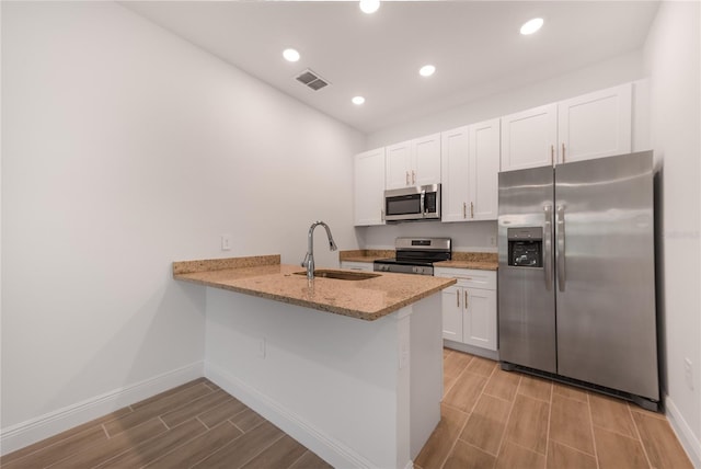 kitchen featuring sink, kitchen peninsula, white cabinetry, stainless steel appliances, and light wood-type flooring