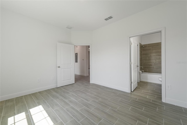 unfurnished bedroom featuring light wood-type flooring and ensuite bath