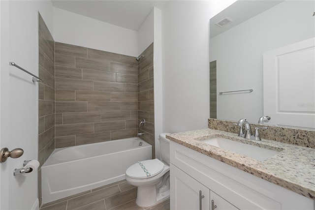 full bathroom with tiled shower / bath, vanity, and toilet