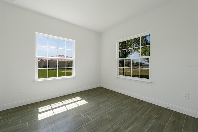 spare room with dark wood-type flooring and plenty of natural light