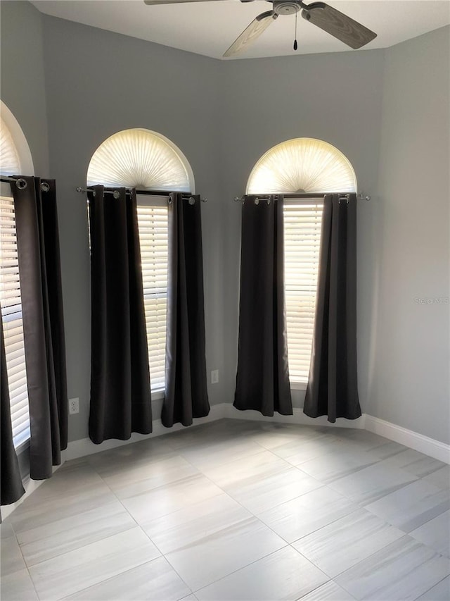 unfurnished room featuring a healthy amount of sunlight, light tile patterned floors, and ceiling fan