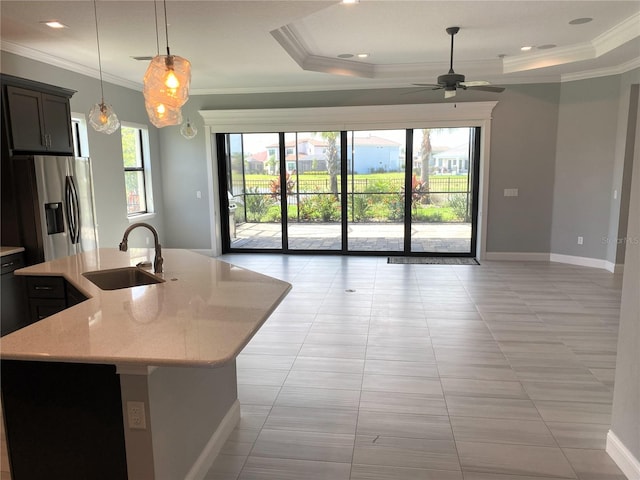 kitchen featuring light stone counters, hanging light fixtures, sink, a kitchen island with sink, and stainless steel fridge with ice dispenser