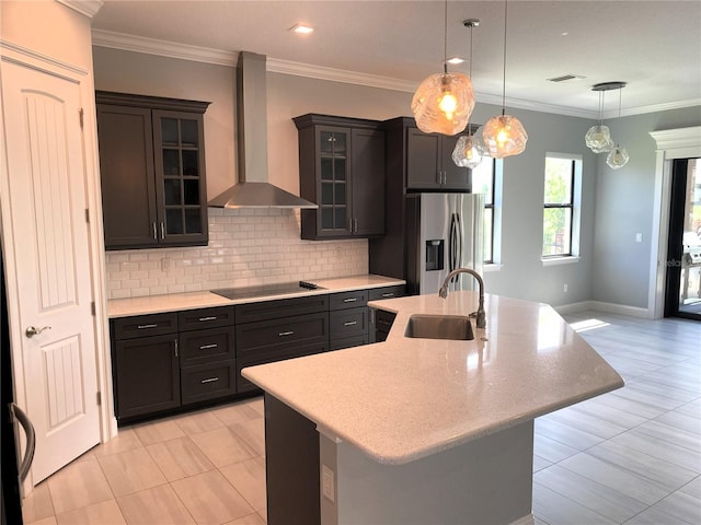 kitchen featuring sink, a kitchen island with sink, wall chimney exhaust hood, black electric stovetop, and a breakfast bar area