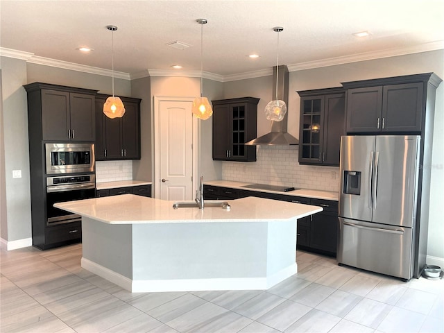 kitchen featuring sink, an island with sink, wall chimney exhaust hood, stainless steel appliances, and decorative light fixtures