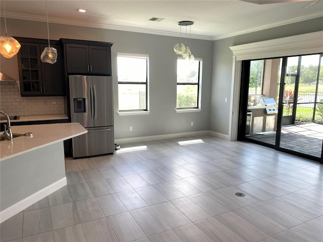 kitchen featuring dark brown cabinets, hanging light fixtures, backsplash, crown molding, and stainless steel fridge