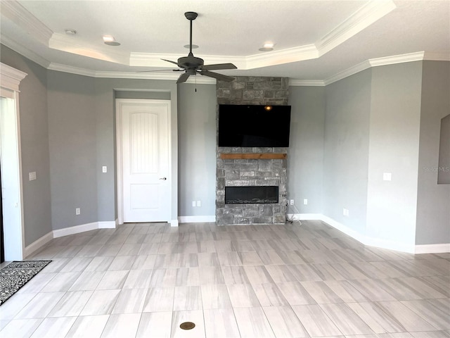 unfurnished living room featuring ornamental molding, a fireplace, a tray ceiling, and ceiling fan