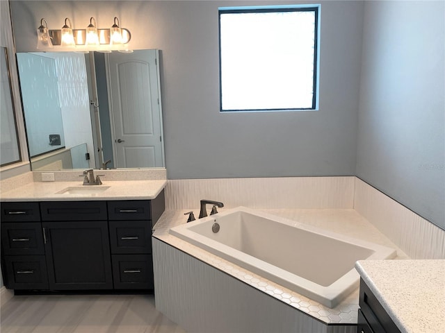 bathroom featuring tiled tub and vanity