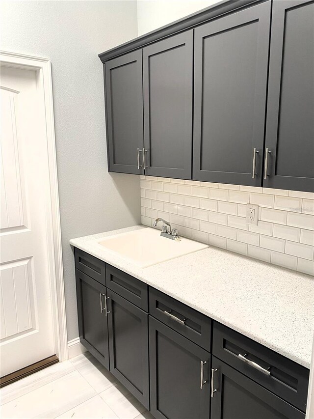 kitchen with sink, light tile patterned floors, light stone counters, and tasteful backsplash