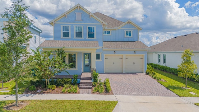 view of front of home with board and batten siding, a garage, a front lawn, and decorative driveway