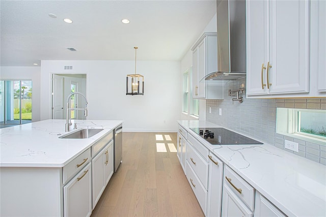 kitchen with a kitchen island with sink, sink, wall chimney range hood, light hardwood / wood-style flooring, and stainless steel dishwasher