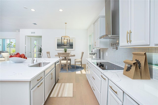 kitchen with black electric cooktop, a sink, wall chimney range hood, dishwasher, and pendant lighting