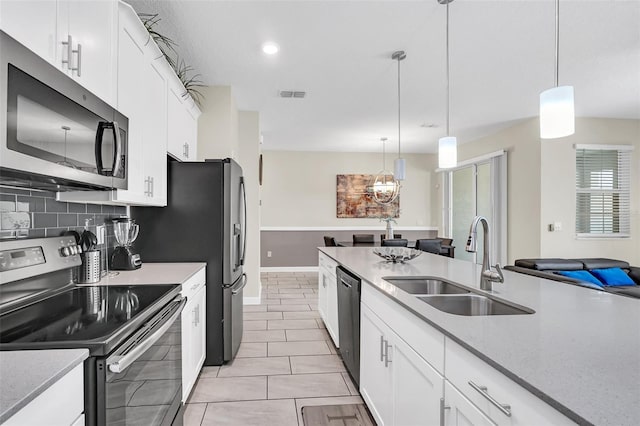 kitchen featuring pendant lighting, sink, backsplash, white cabinetry, and stainless steel appliances