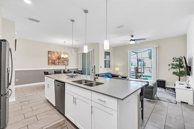 kitchen featuring white cabinets, stainless steel appliances, ceiling fan, a center island with sink, and sink