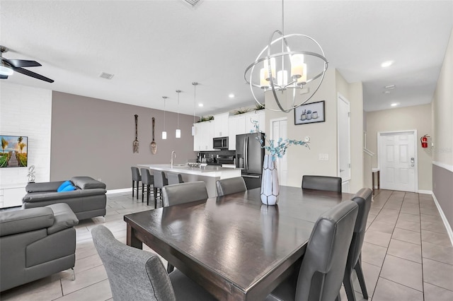 tiled dining area with ceiling fan with notable chandelier and sink