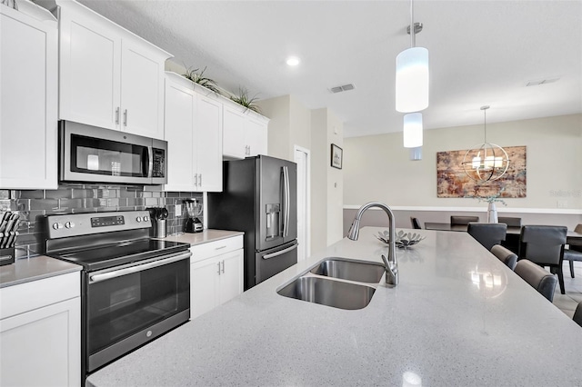 kitchen featuring appliances with stainless steel finishes, sink, pendant lighting, and white cabinets