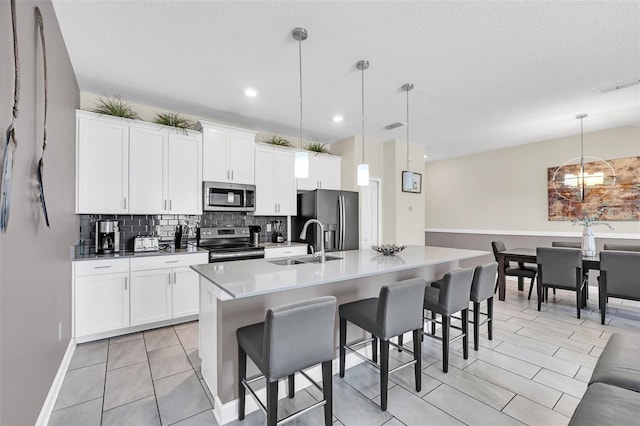 kitchen featuring pendant lighting, stainless steel appliances, a center island with sink, and a breakfast bar