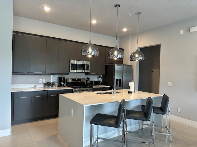 kitchen featuring a textured ceiling, a kitchen island with sink, sink, and stainless steel appliances