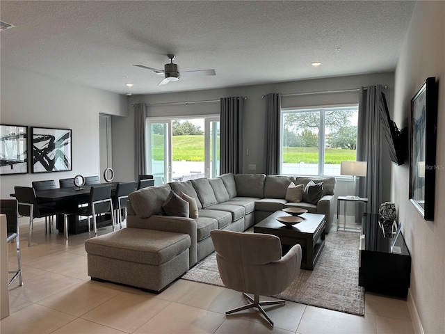 living room with ceiling fan, a textured ceiling, and light tile patterned flooring