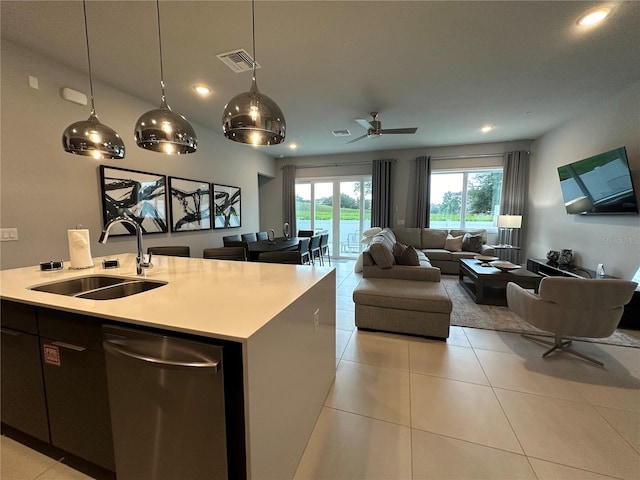 kitchen with hanging light fixtures, an island with sink, dishwasher, light tile patterned floors, and sink