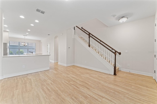 unfurnished living room with light hardwood / wood-style floors and an inviting chandelier