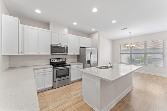 kitchen with hanging light fixtures, a kitchen island with sink, white cabinetry, appliances with stainless steel finishes, and a notable chandelier