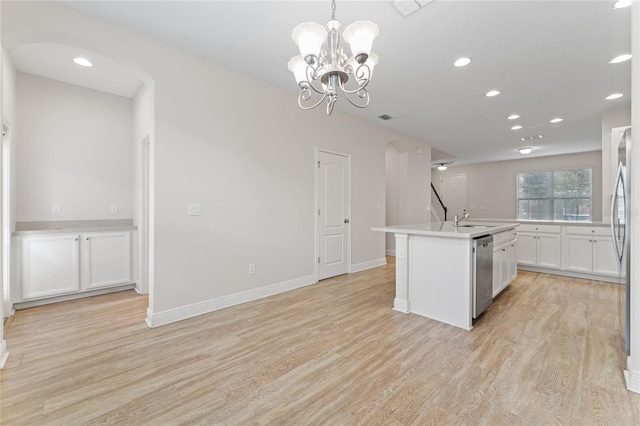 kitchen with hanging light fixtures, white cabinets, stainless steel appliances, light wood-type flooring, and a center island with sink