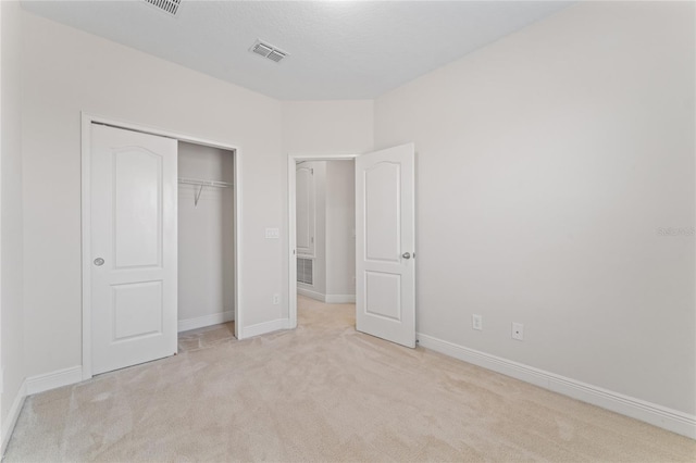 unfurnished bedroom featuring a closet and light colored carpet