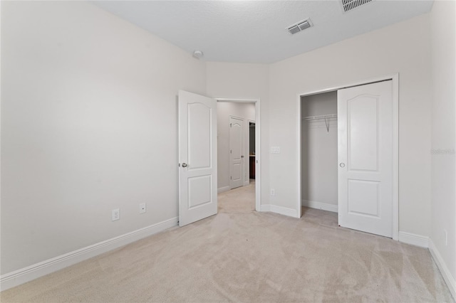 unfurnished bedroom with light carpet and a closet