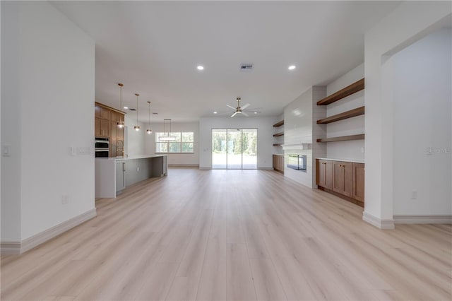 unfurnished living room featuring ceiling fan and light wood-type flooring