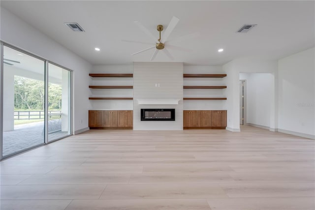 unfurnished living room featuring a large fireplace, ceiling fan, and light hardwood / wood-style flooring