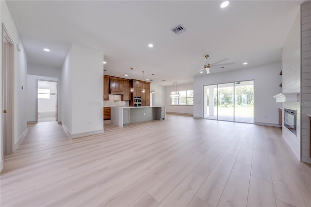 unfurnished living room featuring a fireplace, ceiling fan, and light hardwood / wood-style flooring