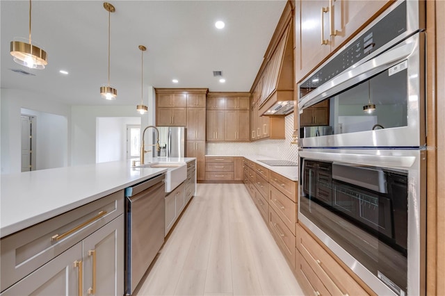 kitchen with decorative backsplash, stainless steel appliances, light hardwood / wood-style flooring, decorative light fixtures, and sink