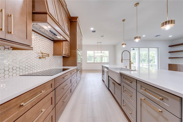 kitchen with custom exhaust hood, hanging light fixtures, sink, and a wealth of natural light