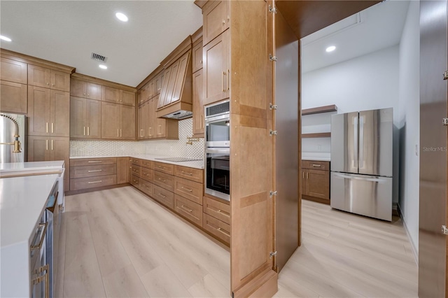 kitchen featuring appliances with stainless steel finishes, backsplash, light hardwood / wood-style floors, and custom exhaust hood