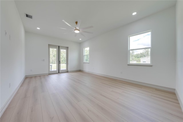 spare room featuring light wood-type flooring, ceiling fan, and french doors