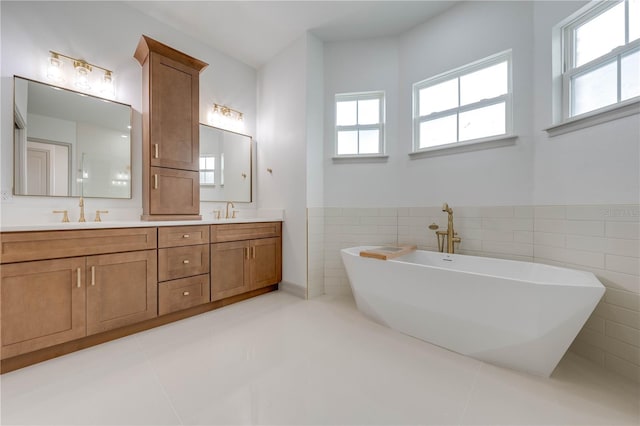 bathroom featuring tile walls, tile patterned floors, a bath, and vanity