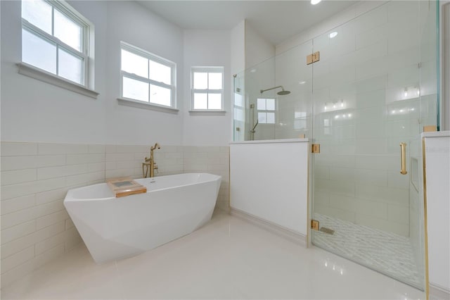 bathroom featuring tile walls and separate shower and tub