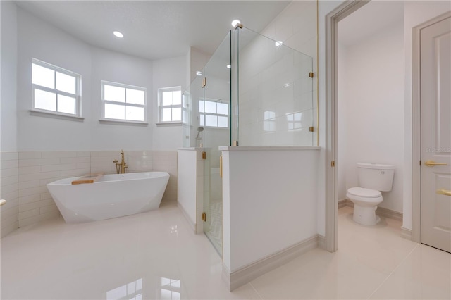 bathroom featuring tile walls, toilet, a shower with door, and tile patterned floors